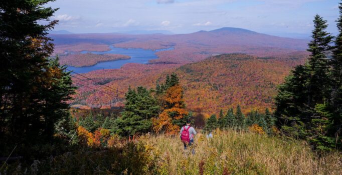 A person hikes down a ski trail at a ski resort in the fall.