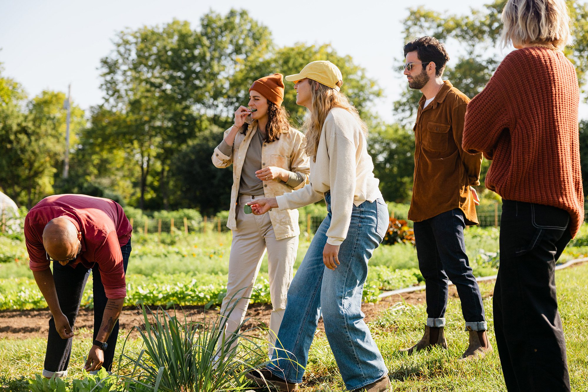 A group of people standing outside on a sunny day at a farm. 