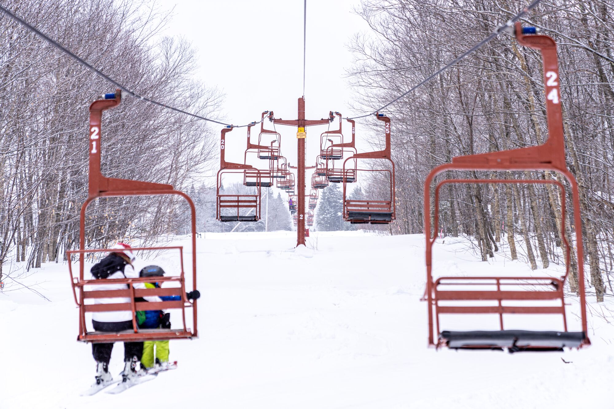 Two people on a chairlift outside in the winter. 