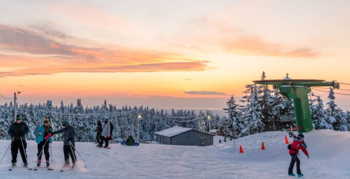 A group of skiers looking at a sunset in Vermont.