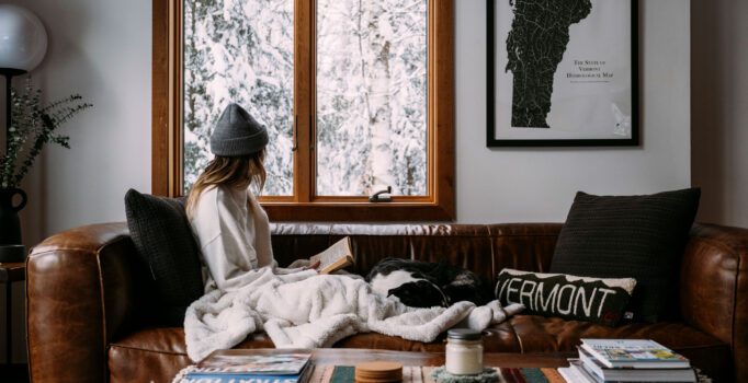 A person sits on a couch reading on a wintery day.