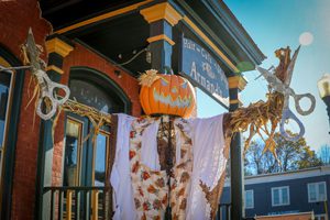 Halloween decorations showcase a scarecrow with pumpkin head.