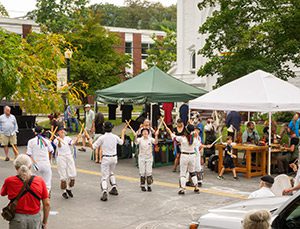 Four people, dressed in white, perform on a street.