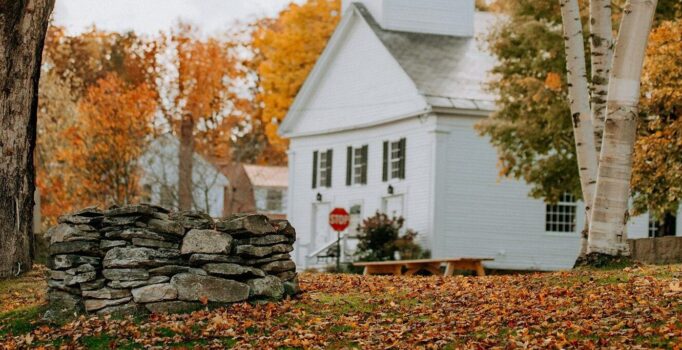 A white building among orange leaves both on trees and on the ground. 