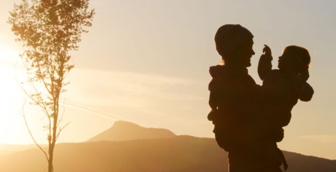 A Family embrace with a mountainous backdrop at sunset.