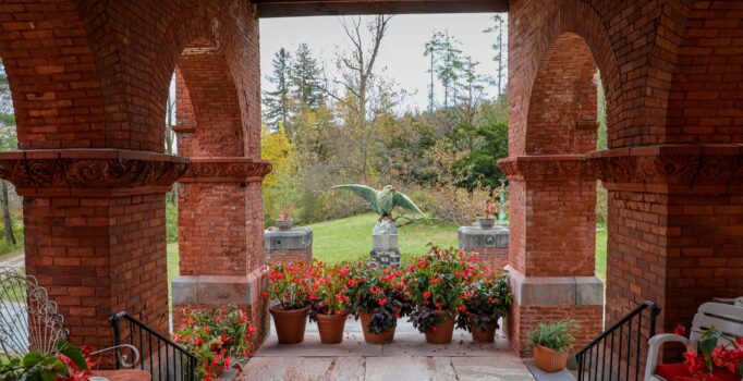 Seen from inside a brick building, a veranda supported by large brick pillars in the fall.