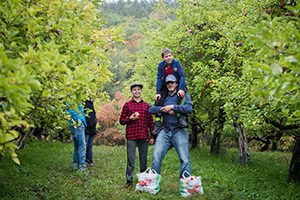 A family picks apples in an apple orchard in the fall.