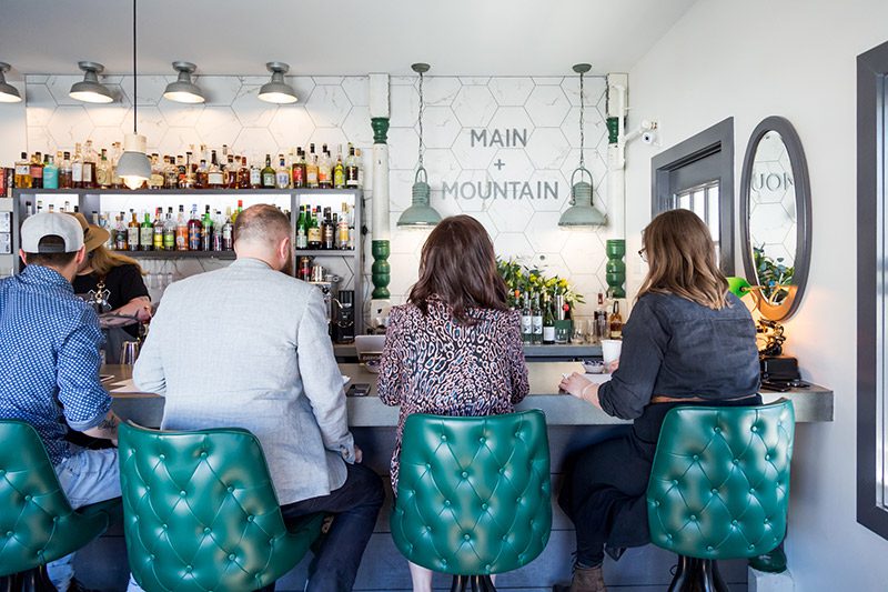 Four people sit at a bar.