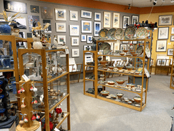 An indoor view of wooden fixtures with artisan crafts in front of walls covered with art.