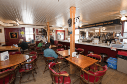 An array of chairs and tables surround counter with a sign above that reads Barnard General Store.