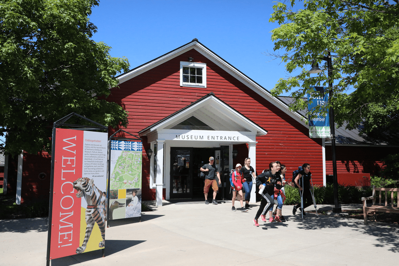 People walk in the front doors of a red museum.