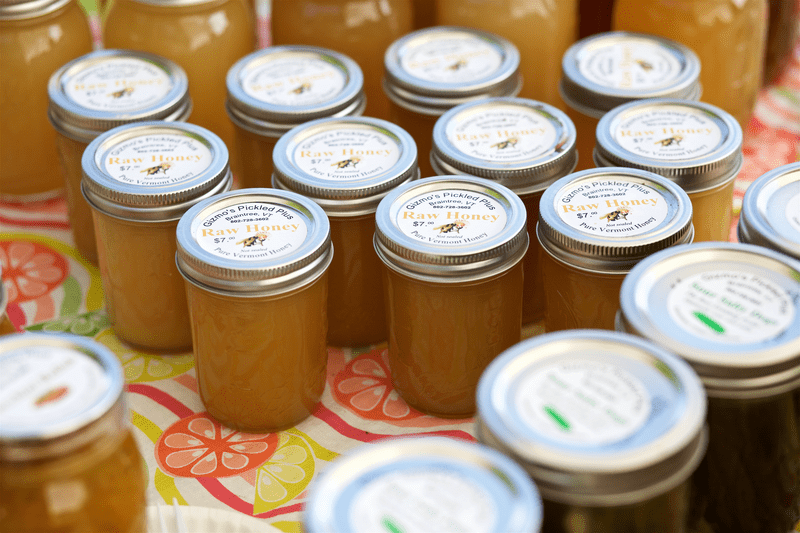 Cans of honey are displayed on a table for sale.