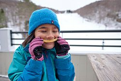 A child holds a curved French fry up to her mouth to look like a smile.