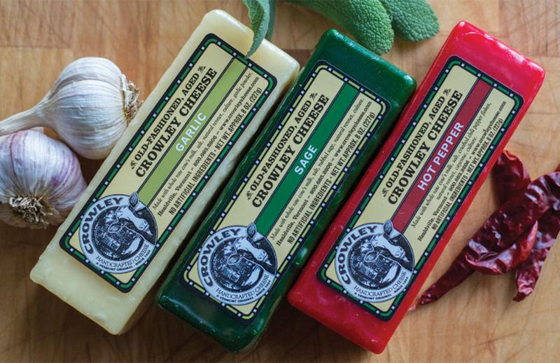 Seen from above, three blocks of cheese are displayed on a wooden cutting board.