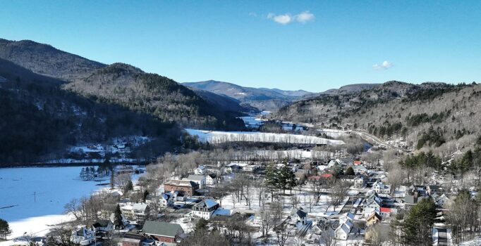 Seen from above, a rural mountain town surrounded by mountains in the winter.