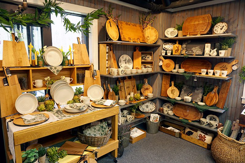 Wooden shelves display an array of wood plats, rolling pins, and other goods in a store.