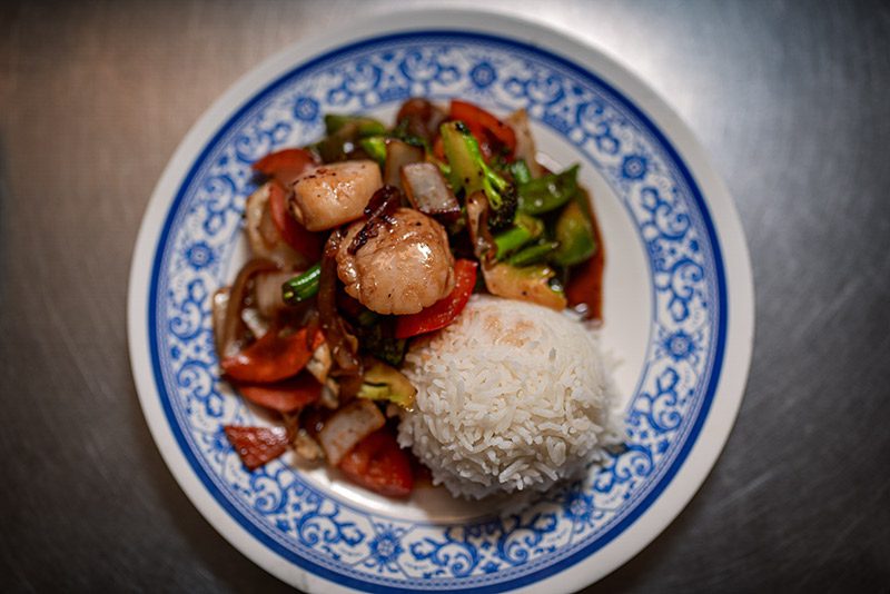 Seen from above and looking down, a late of Thai food on a white and blue plate.