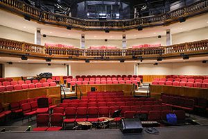 Seen from a performing stage, rows of red seats in a performance arts center.