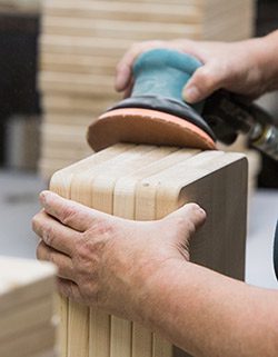 Close view of a person using a sander to finish wooden cutting boards.