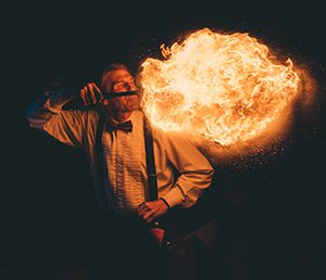 A person performs a fire-breathing show in the dark.