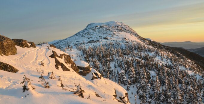 An exposed mountain peak, covered in snow, is seen in the early morning light.