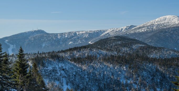 Seen from afar, a ski resort and exposed mountain peak covered in snow.