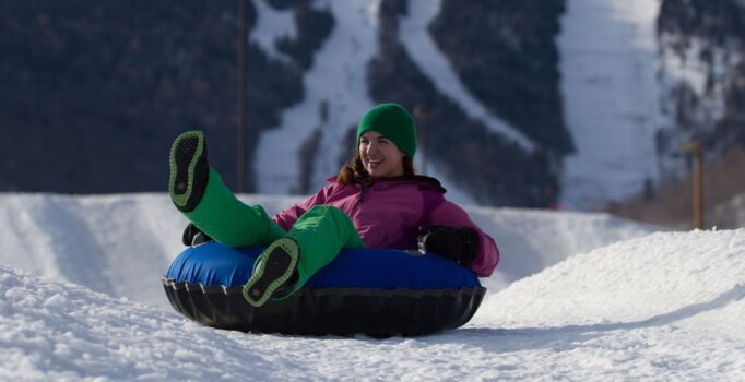 A person rides on a tube down a snowy slope.