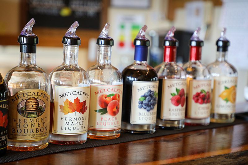 Liquor bottles, branded Metcalffe's, are displayed on a wooden bar.