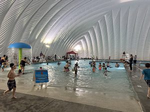 A group of people swim and plan in an indoor pool.