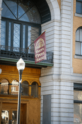 A red flag hang above an old theater door that reads Barre Opera House.