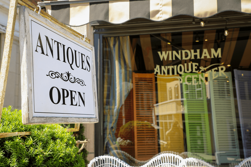 A storefront is visible next to a sign that reads Antiques Open.