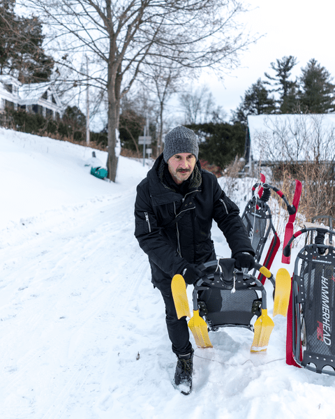 A person is laying a sled down on the snow.