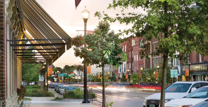 A historic downtown after rainfall, with restaurants and shops visible in brick buildings lining sidewalks.
