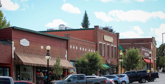 Brick buildings line a town street on a warm summer day.