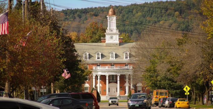 Seen from afar, down a street, is a large brick building that reads Green Mountain College.