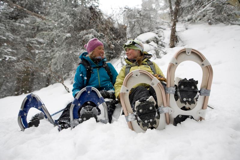 Two people with snowshoes on sitting in the snow in Vermont.