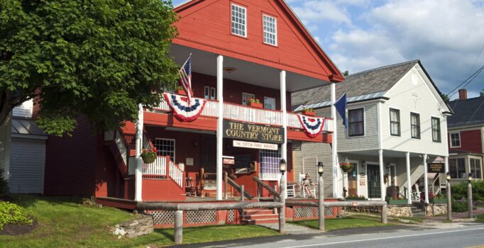 A red building with white trim and a sign reading "The Vermont Country Store," adjacent to a white structure.