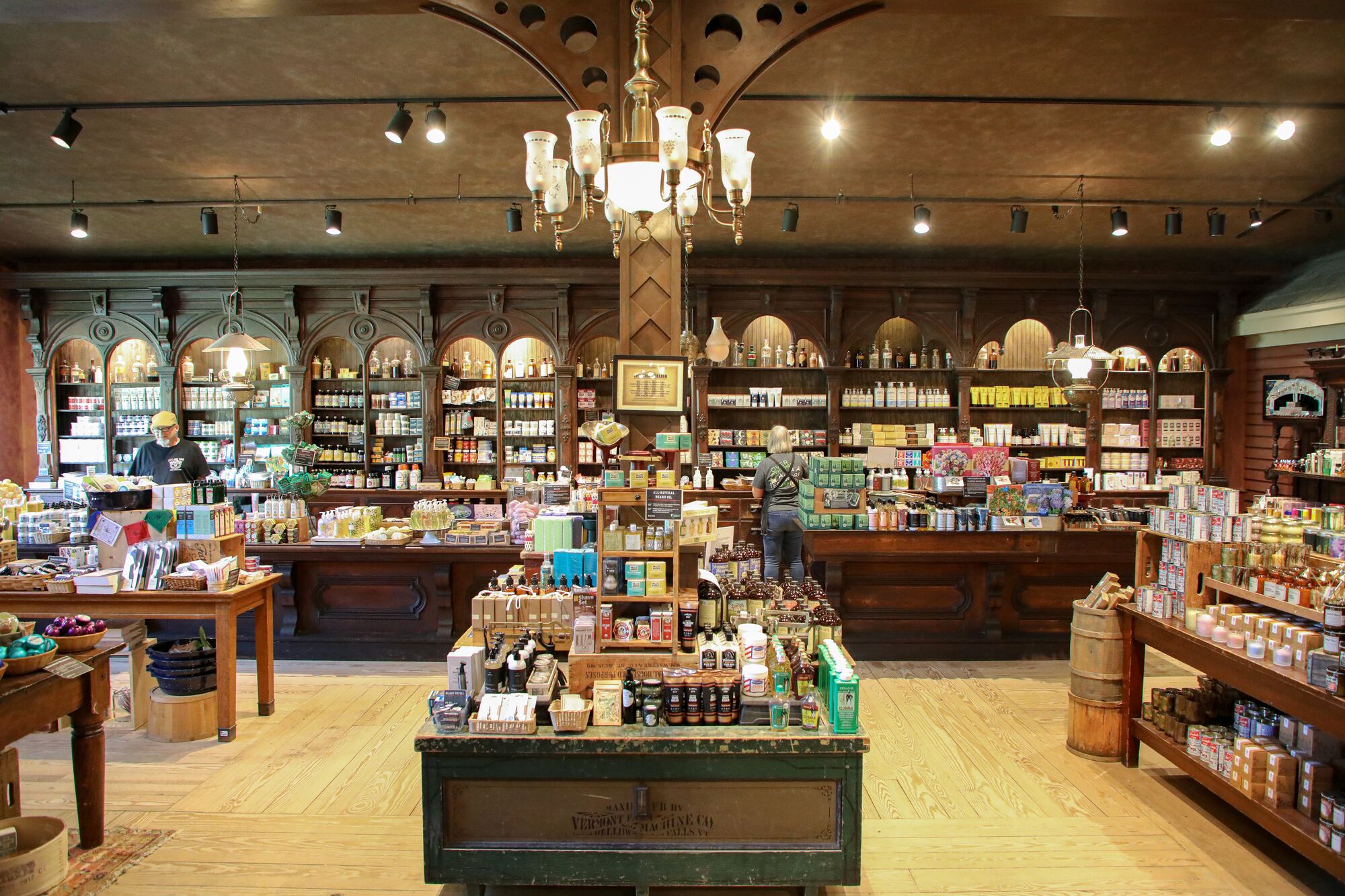 The inside of a country store with wooden floors and shelves and colorful merchandise available throughout.