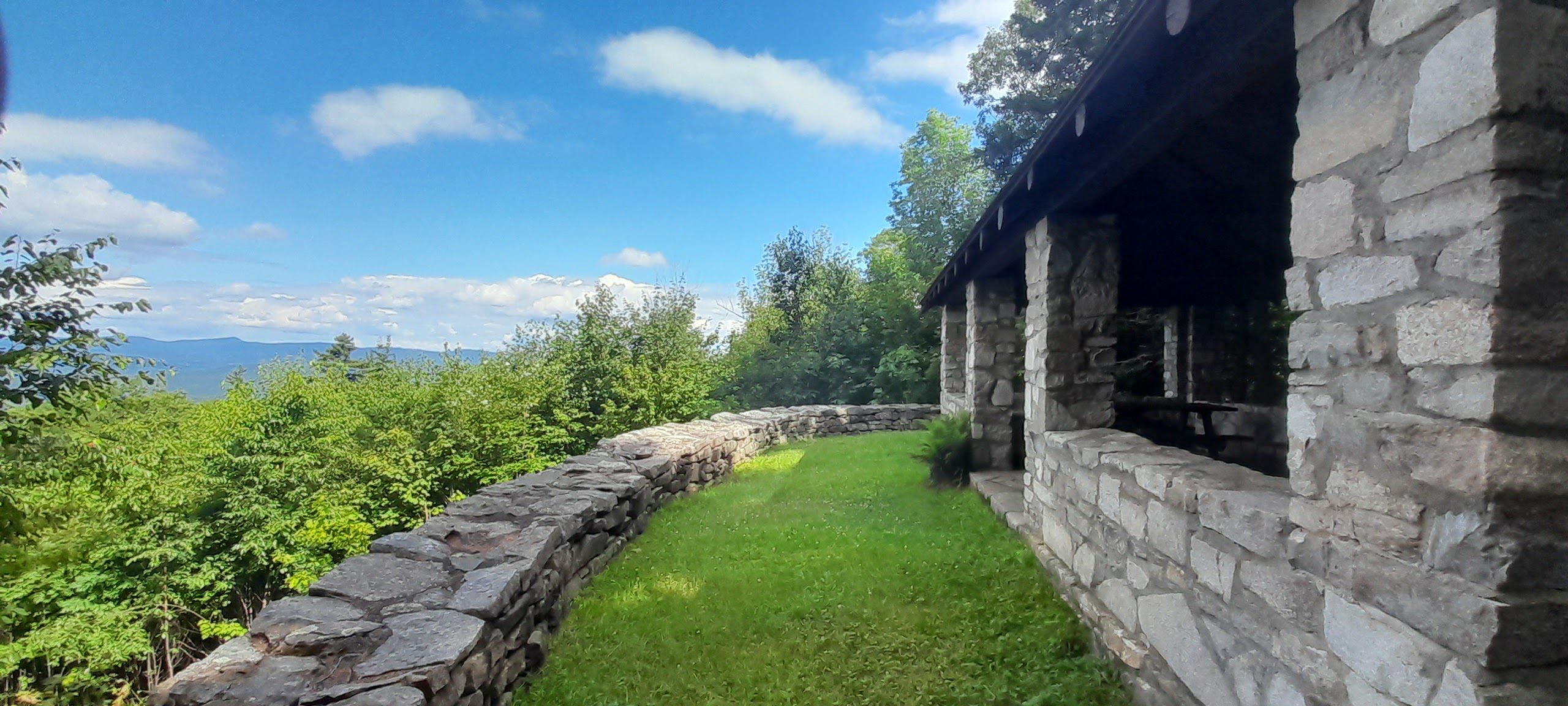 A building seen from outside in the summer with a mountain view on the left side.