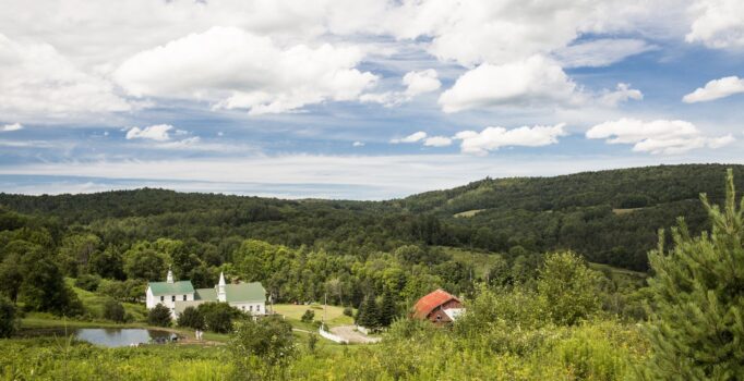 Buildings are visible along a trail through rolling green hills.