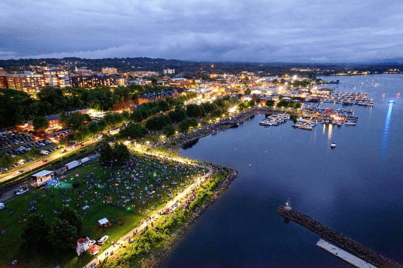 Seen from above, a historic downtown at night, with lights reflecting on a lake.