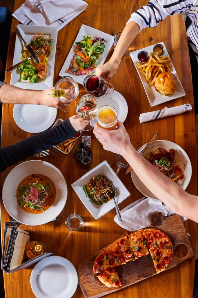 Various dishes seen from above on a wooden table with hands pouring and serving.