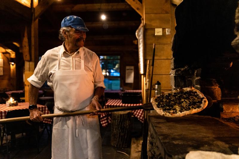 American Flatbread has delicious wood-fired pizzas and a large lawn for sprawling out after a ride. Pizza maker putting pizza in brick oven.