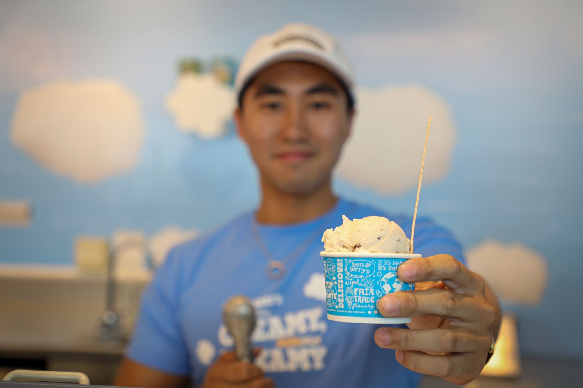 An ice cream cup is handed across by a young man.