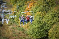 A chair lift surrounded by red, yellow and orange fall foliage.