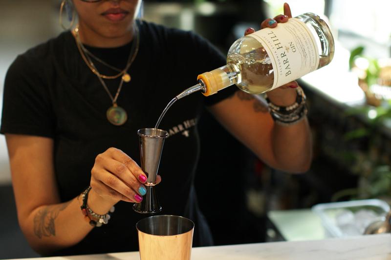 A person mixes a drink at a bar indoors.