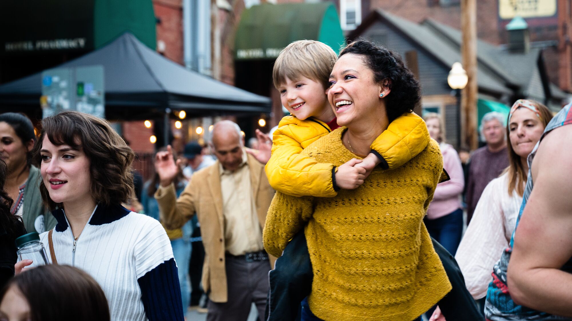 A person carries a child through a street fair in Vermont.