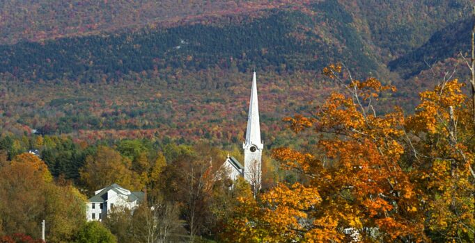 A white steeple surrounded by colorful fall foliage in Vermont.