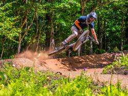 A mountain bike cyclist gets air off an embankment in Vermont.