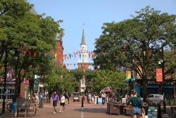 People walk in a pedestrian mall with a steeple in the background in Vermont.